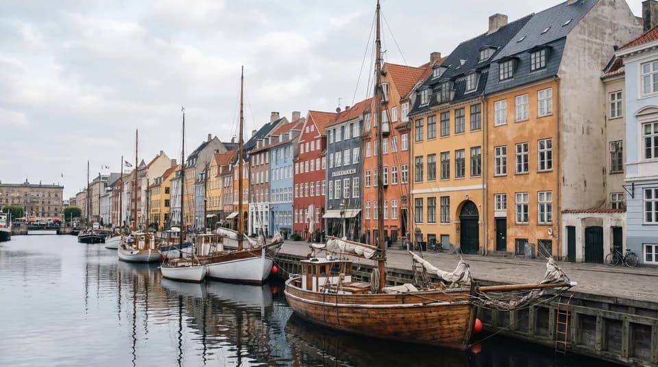Nyhavn i København med farvede huse langs kanalen og gamle træskibe ved kajen