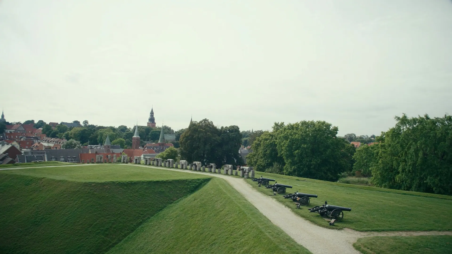 Fredericia Vold med græsklædte bastioner, en række gamle kanoner og byens tage bagved