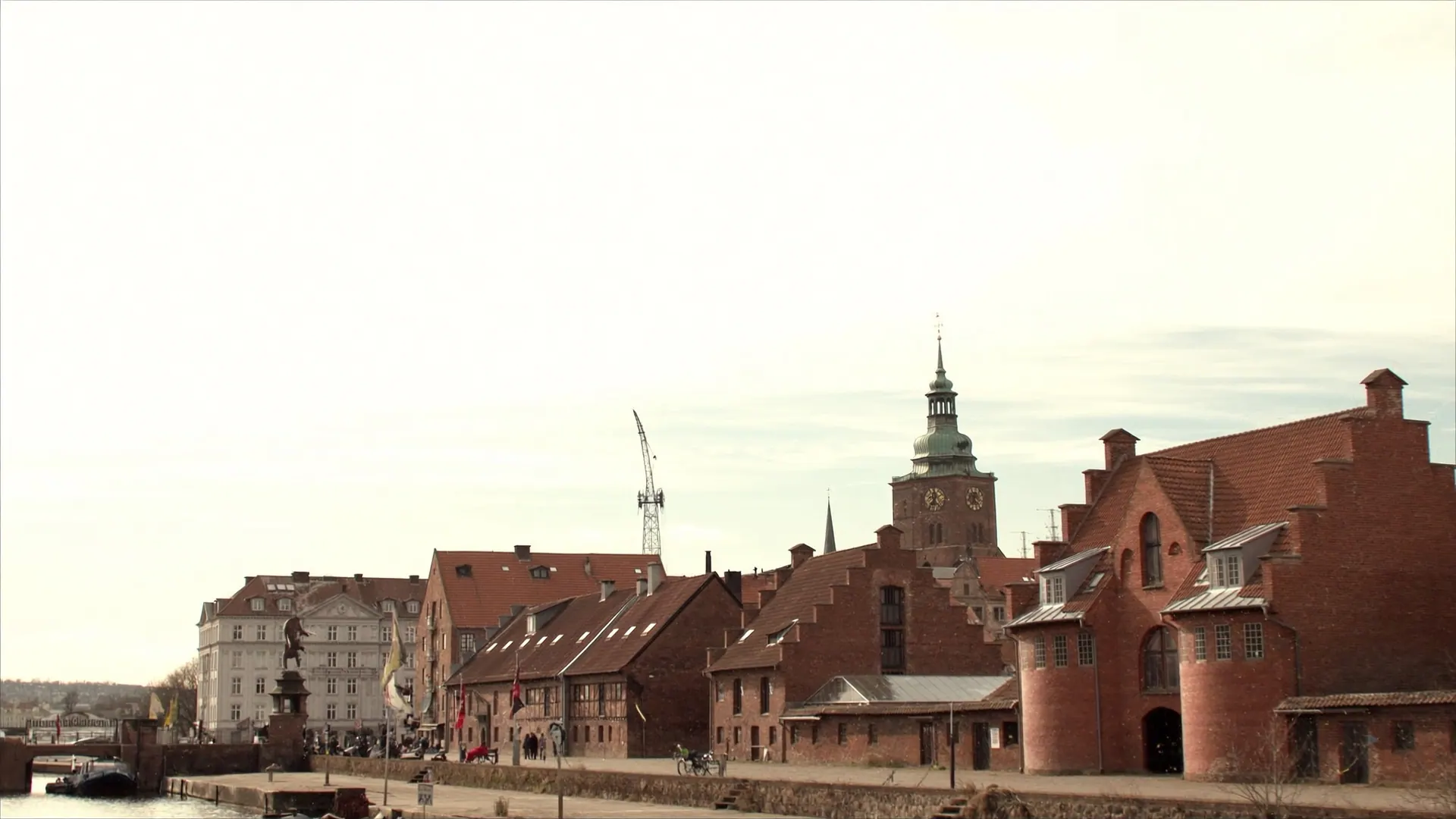 Den gamle bydel i Randers langs Gudenåen med røde pakhuse på kajen og kirketårnet bag tagene